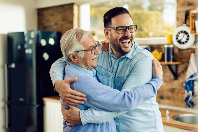 cheerful-mature-man-his-adult-son-embracing-while-greeting-kitchen